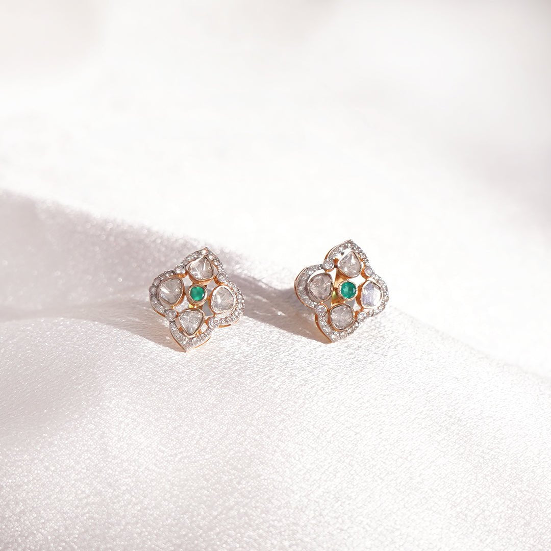 Detailed image of fern-leaf earrings with uncut diamonds and golden frame.