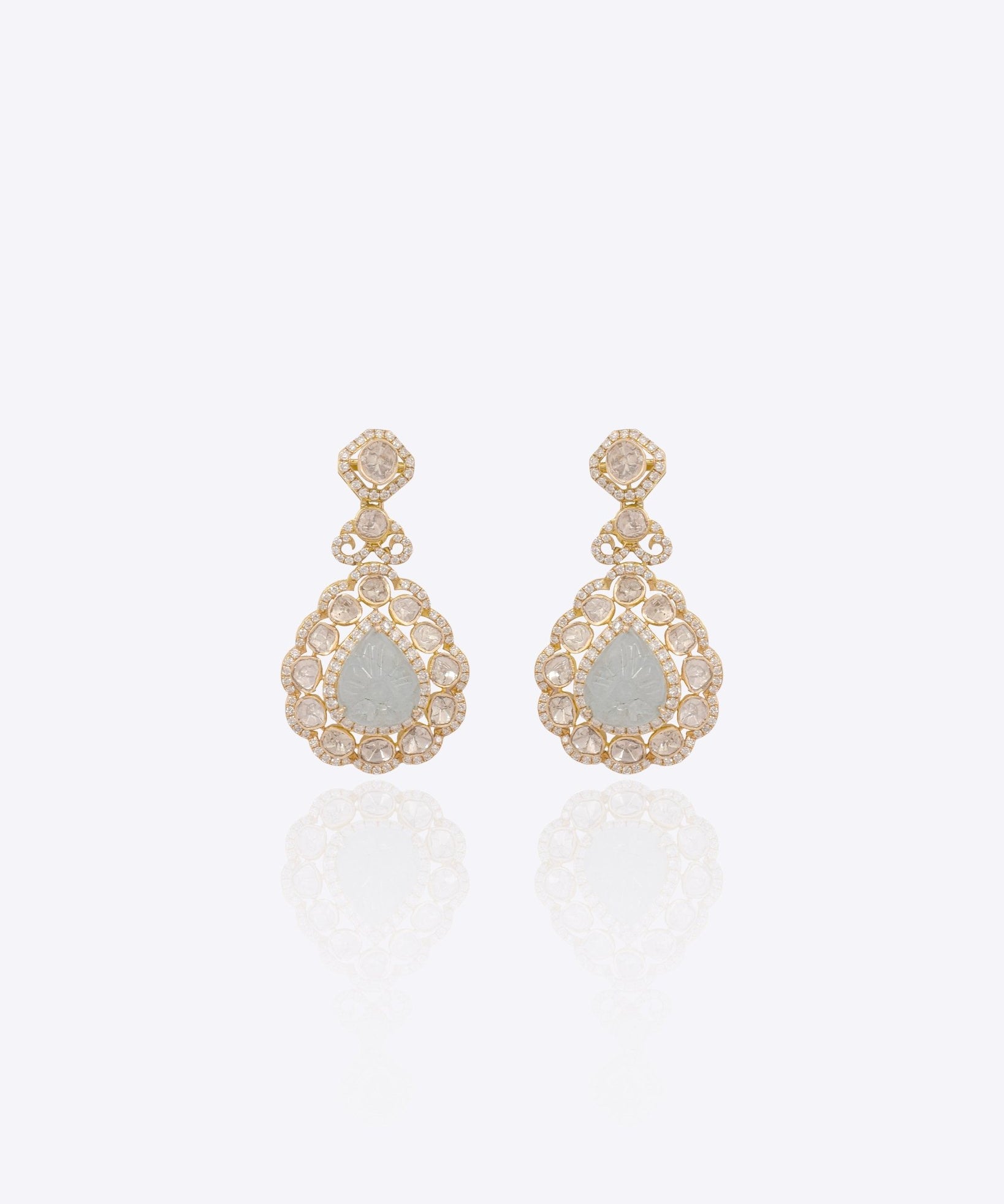 Pair of handcrafted Polki earrings with meenakari back, displayed on a royal blue backdrop.
