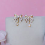 14K gold earrings with a 3D folded bow design and cascading stones.