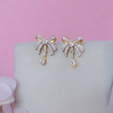 14K gold earrings with a 3D folded bow design and cascading stones.