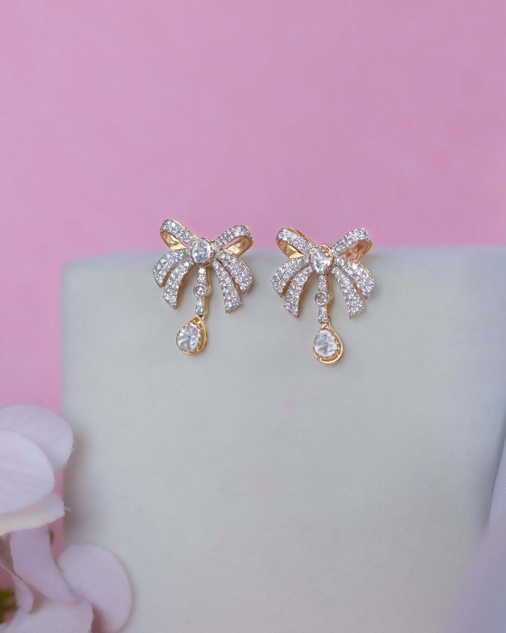14K gold earrings with a 3D folded bow design and cascading stones.