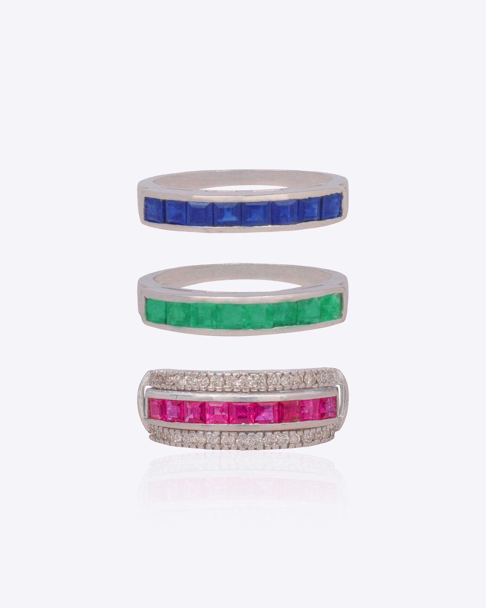 18K white gold stackable ring trio with vivid blue, crimson, and green stones.
