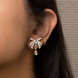 14K gold earrings with a 3D folded bow design and cascading stones.