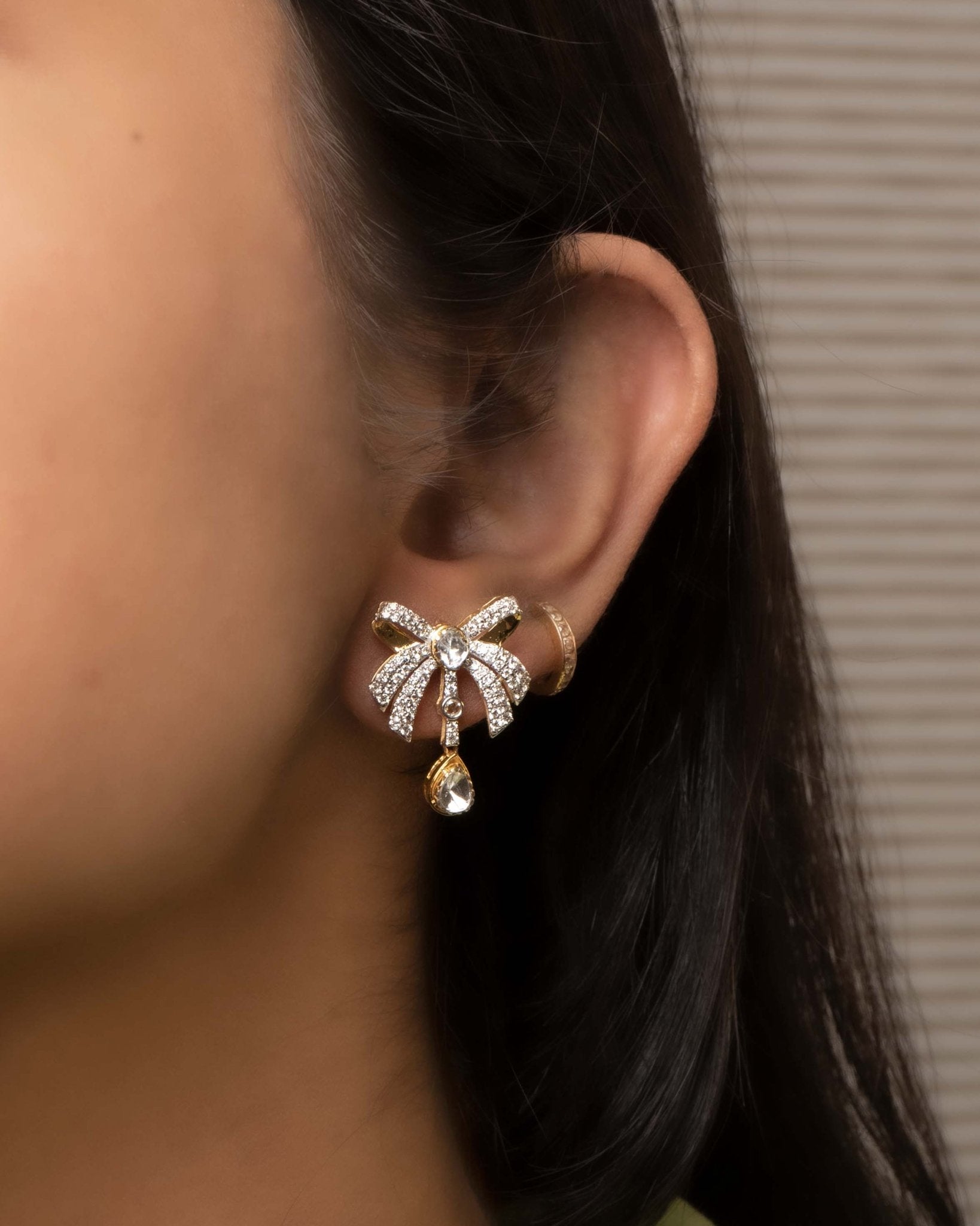 14K gold earrings with a 3D folded bow design and cascading stones.
