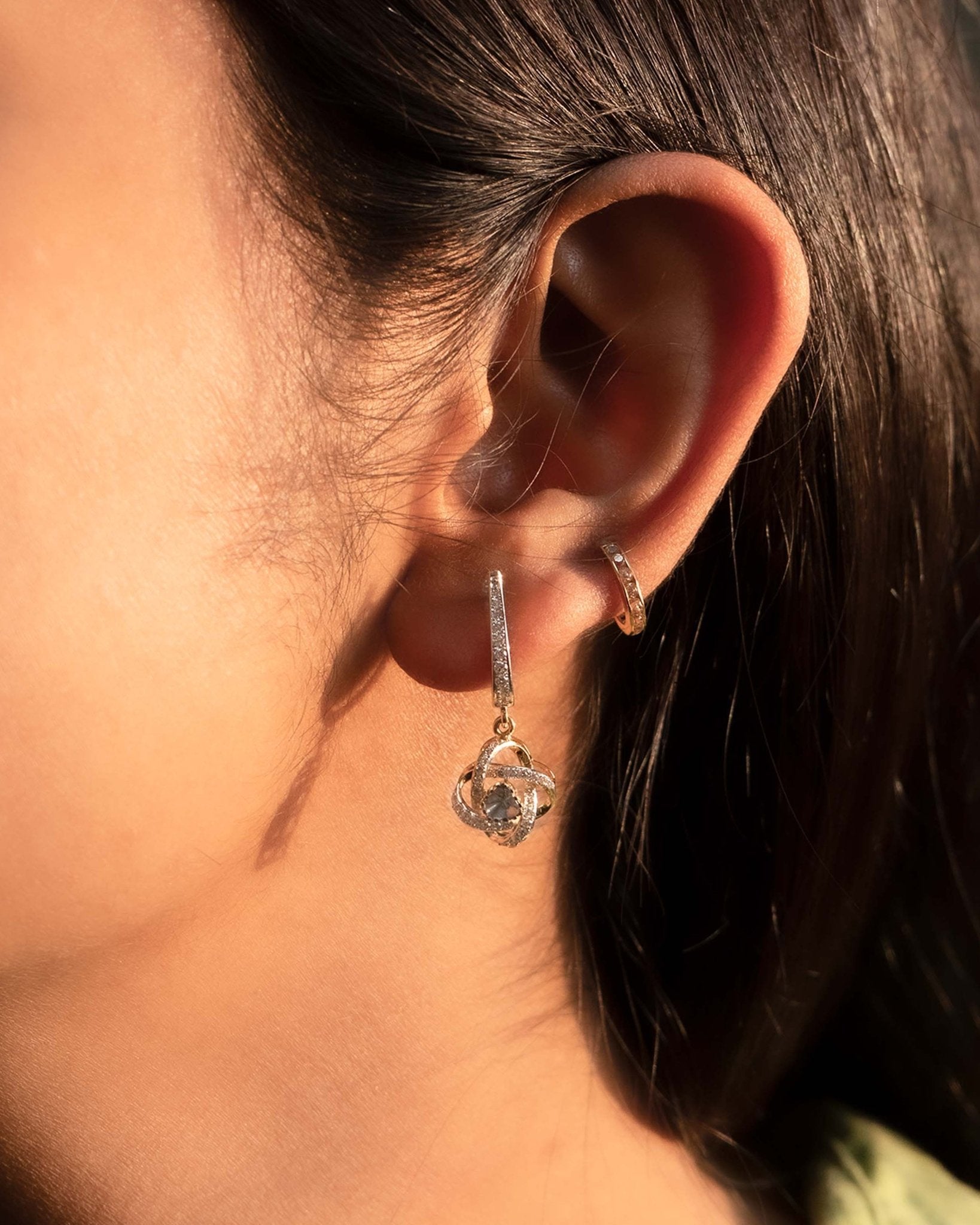 14K gold woven-texture knot earrings with a central luminous stone.