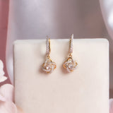 14K gold woven-texture knot earrings with a central luminous stone.
