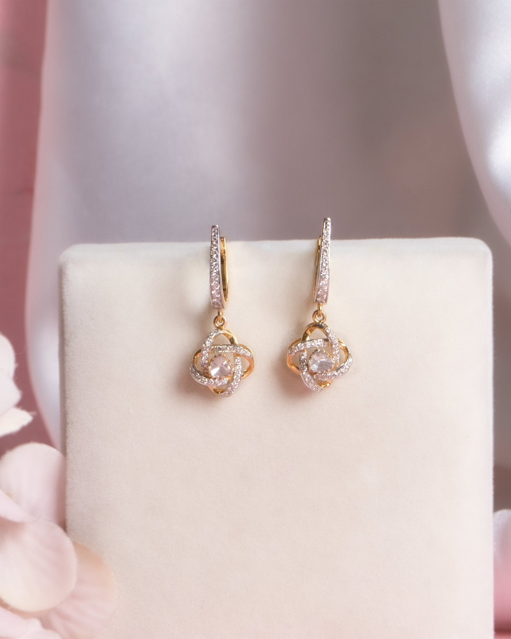 14K gold woven-texture knot earrings with a central luminous stone.