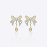 14K gold earrings with a 3D folded bow design and cascading stones.