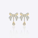 14kt gold earrings featuring a three-dimensional folded bow design with delicate cascading stones for movement.