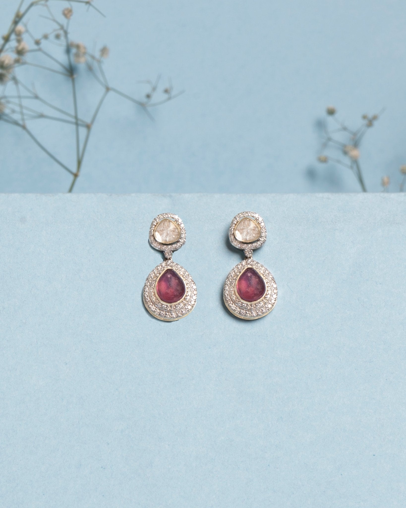 Oval ruby and Polki diamond drop earrings in 14K gold with a double-halo design.
