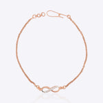 14K gold infinity motif bracelet with a diamond-studded design, worn solo.