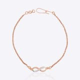 14K gold infinity motif bracelet with a diamond-studded design, worn solo.