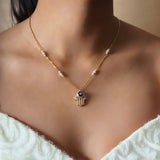 14k gold necklace with an Evil Eye and Hamsa symbol in diamonds