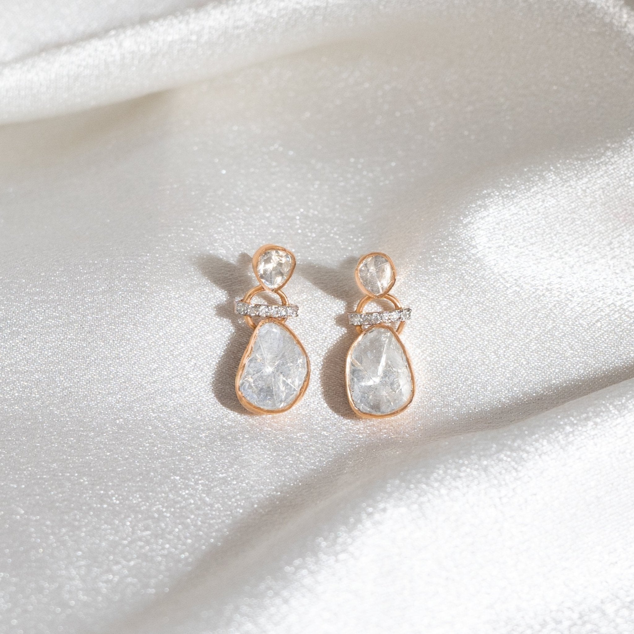 Petite polki earrings with diamond detailing arranged on a pastel velvet fabric.